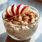 Bowl of applesauce overnight oats topped with fresh fruits and nuts