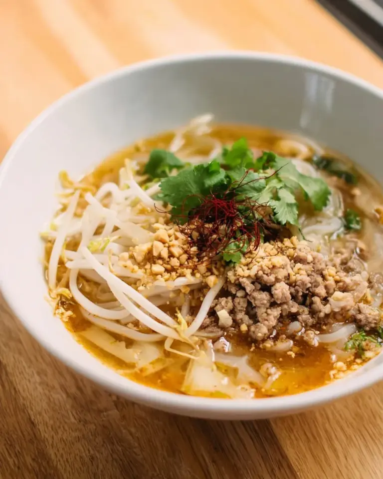 Bowl of Thai Tom Yum Noodle Soup garnished with herbs and spices